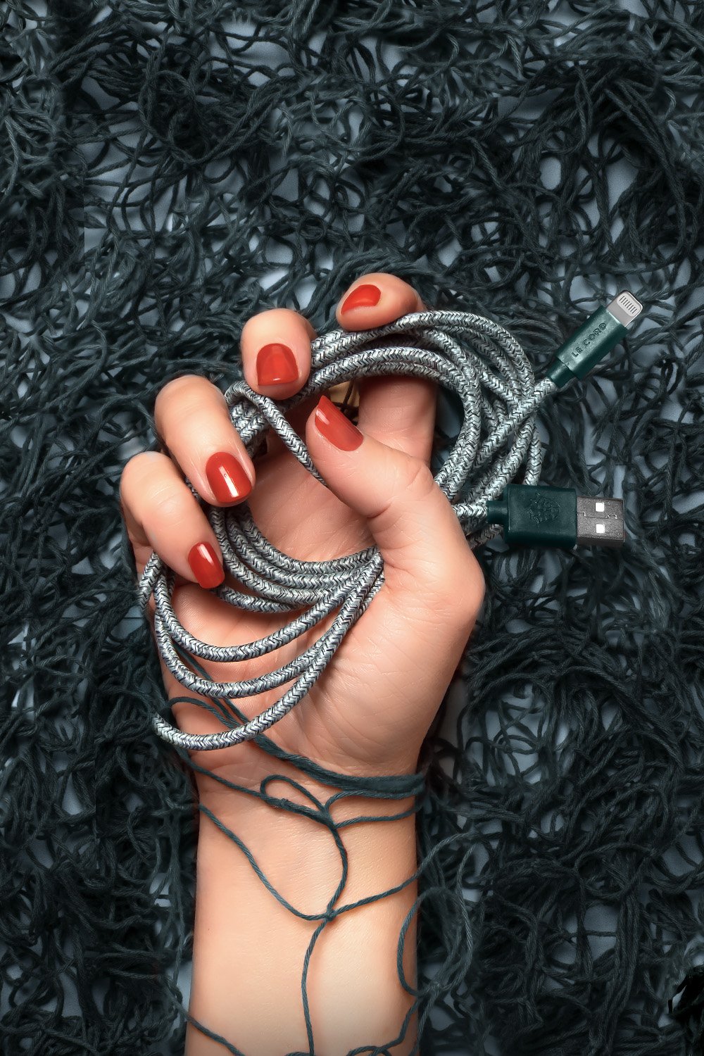 Green iPhone Lightning cable made from recycled fishing nets, featuring a braided textile sleeve and MFI certification.