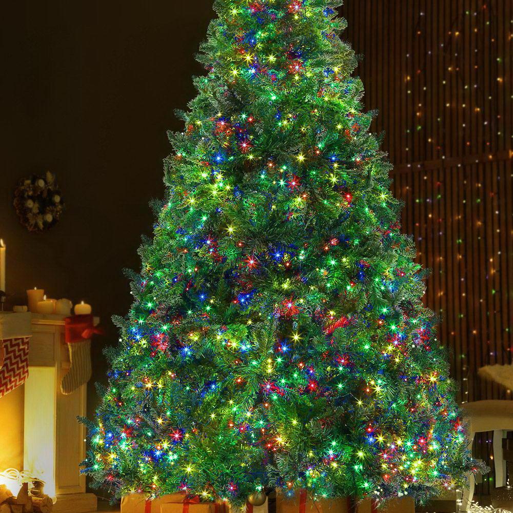 Jingle Jollys 2.4M LED Christmas Tree with multicoloured lights and bushy branches, set up for festive decorations.