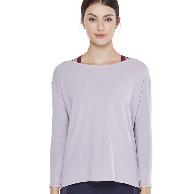 A woman wearing a loose fit long sleeve workout shirt made of Pima cotton, perfect for yoga and casual outings.