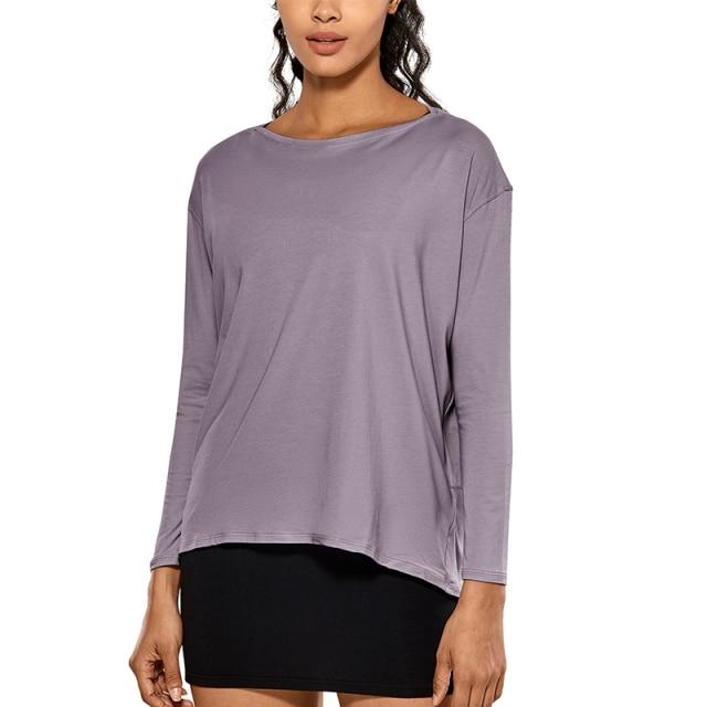 A woman wearing a loose fit long sleeve workout shirt made of Pima cotton, perfect for yoga and casual outings.