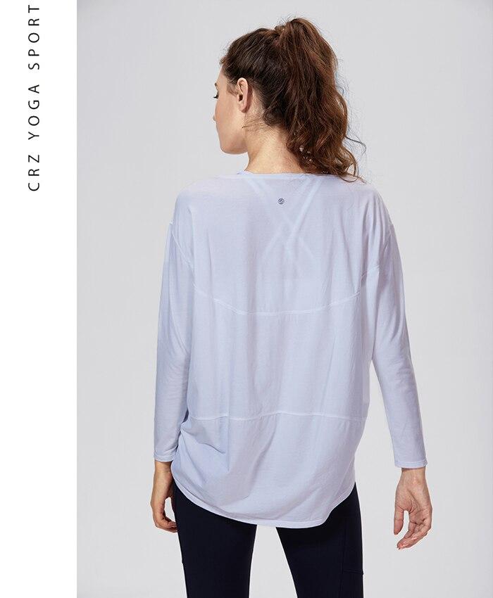 A woman wearing a loose fit long sleeve workout shirt made of Pima cotton, perfect for yoga and casual outings.