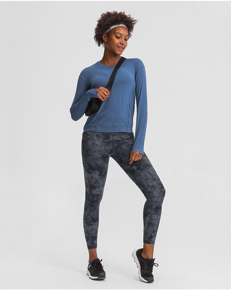 A lightweight long sleeve workout shirt for women, featuring a loose fit and thumb holes, ideal for yoga and fitness activities.