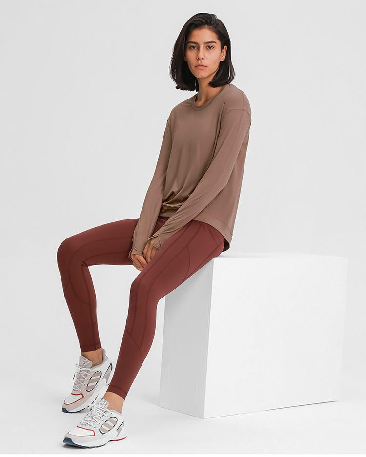 A lightweight long sleeve workout shirt for women, featuring a loose fit and thumb holes, ideal for yoga and fitness activities.