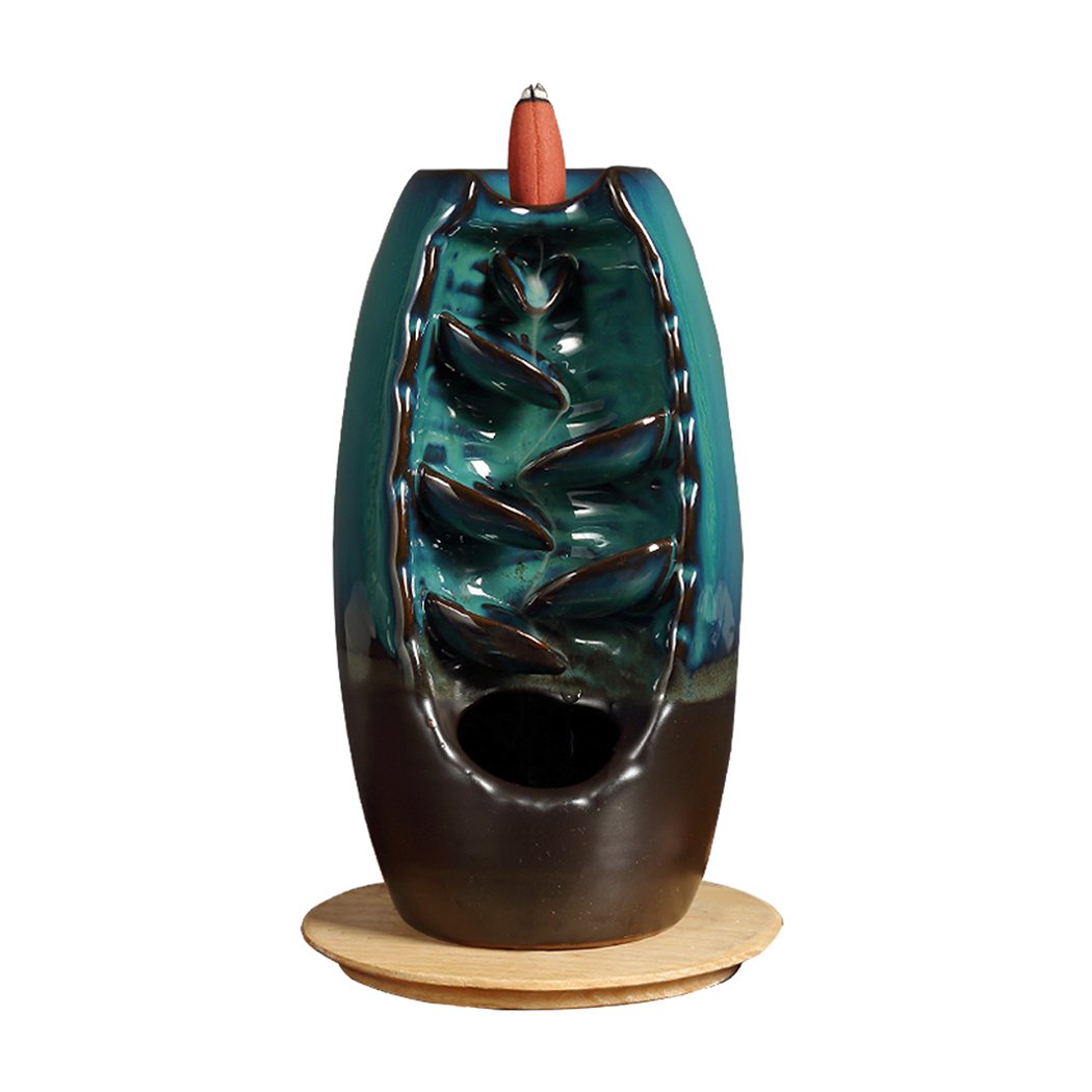 Ceramic incense burner shaped like a mountain waterfall, with smoke cascading downwards, featuring a smooth blue finish and natural incense cones.