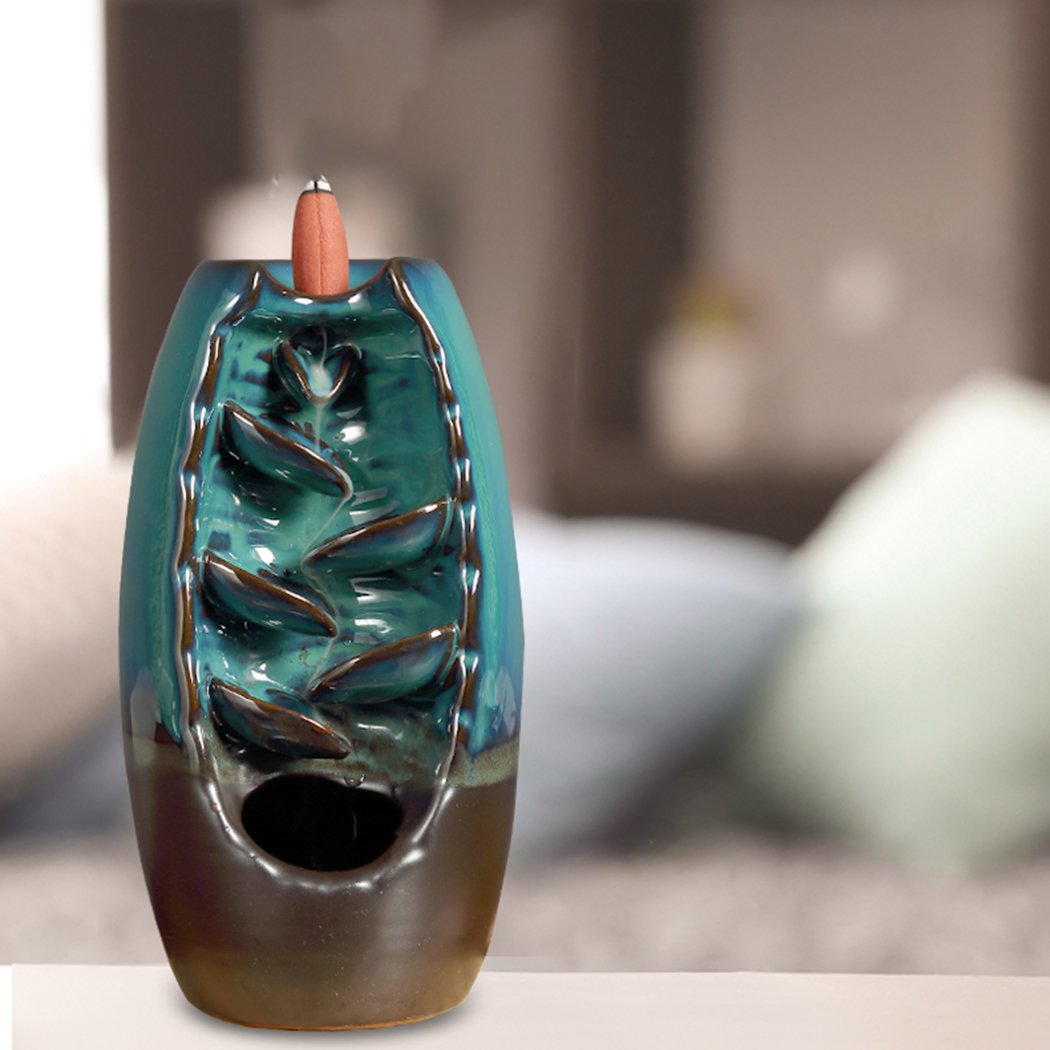 Ceramic incense burner shaped like a mountain waterfall, with smoke cascading downwards, featuring a smooth blue finish and natural incense cones.