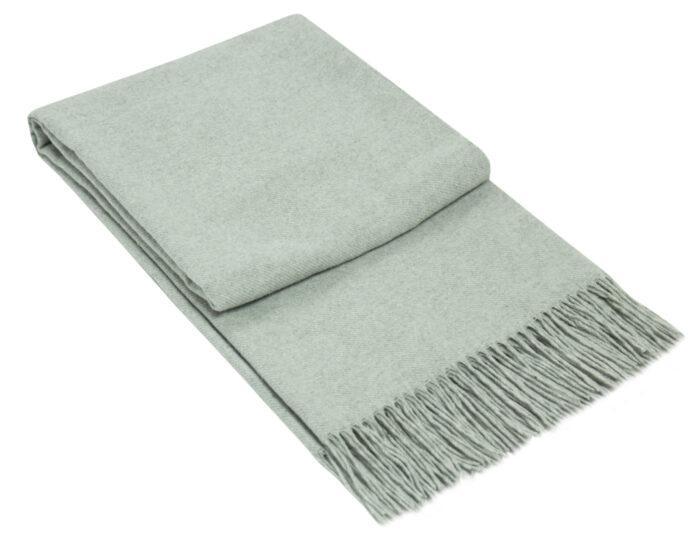 Light grey Paddington throw blanket made from a fine wool blend, elegantly draped over a cozy sofa.