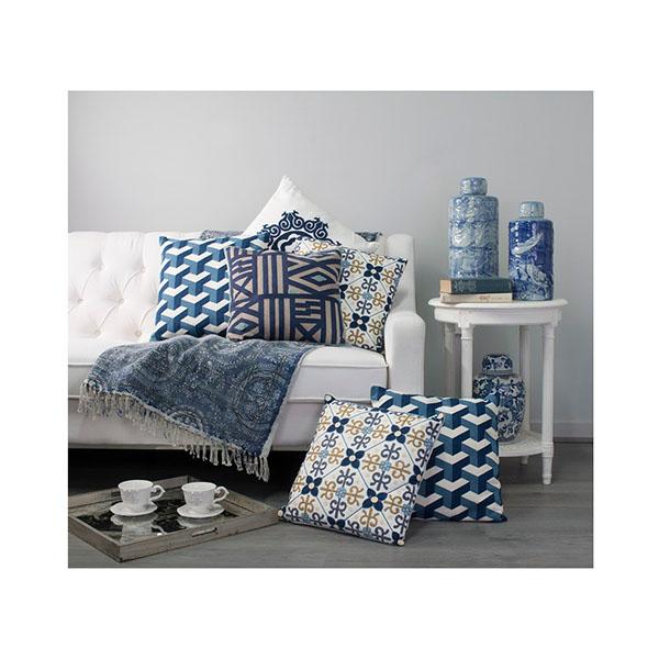 A square cushion featuring a vibrant geometric pattern in taupe, blue, and green, with textured embroidered accents.