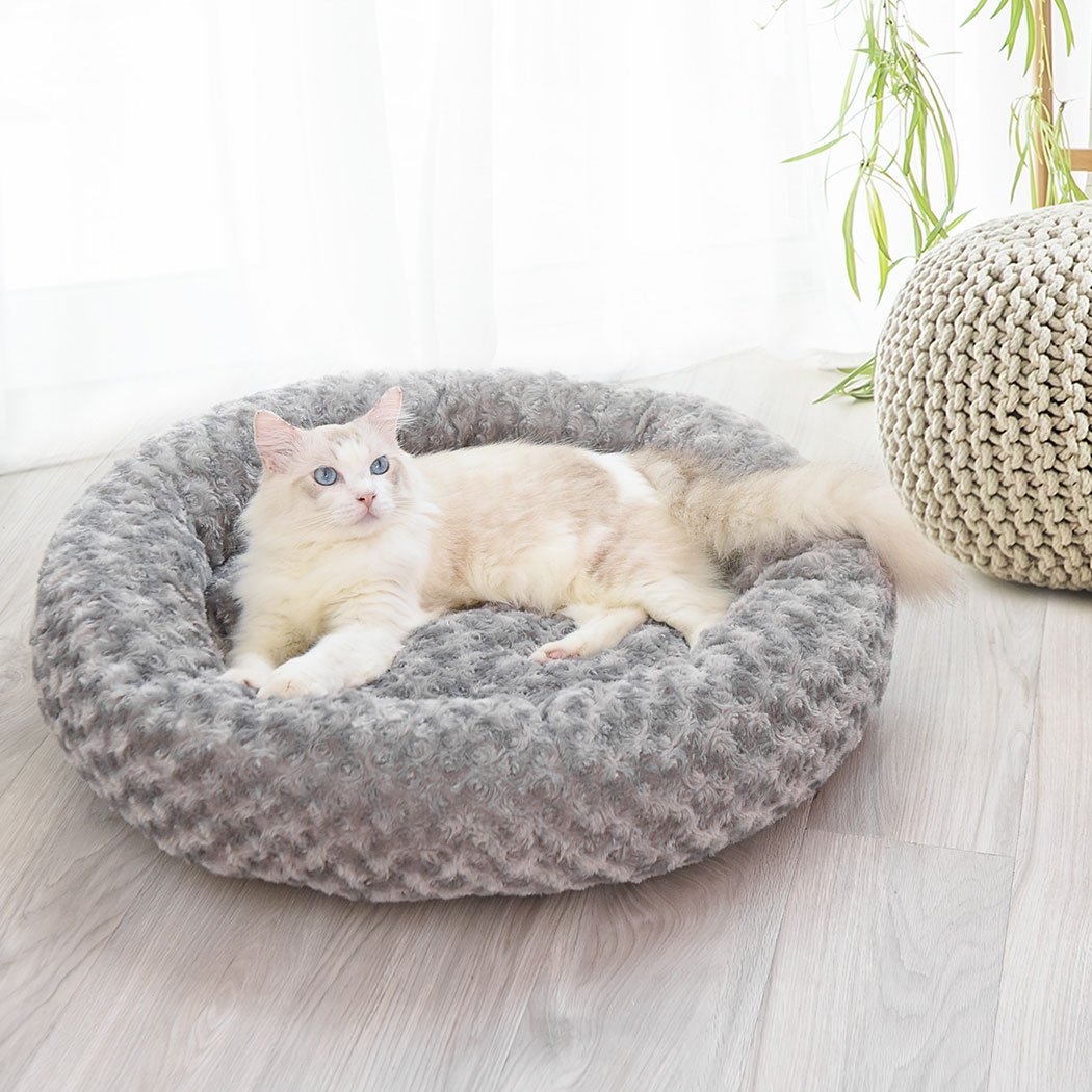 A soft plush donut-shaped pet bed in grey, designed for dogs and cats, featuring a cozy and comfortable interior with an anti-slip bottom.