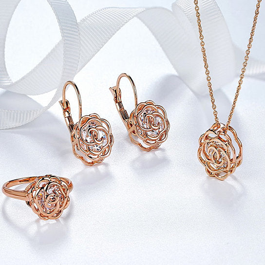 Rose Is A Rose jewelry set featuring a ring, earrings, and pendant in 18kt gold with diamond crystal accents, elegantly displayed.