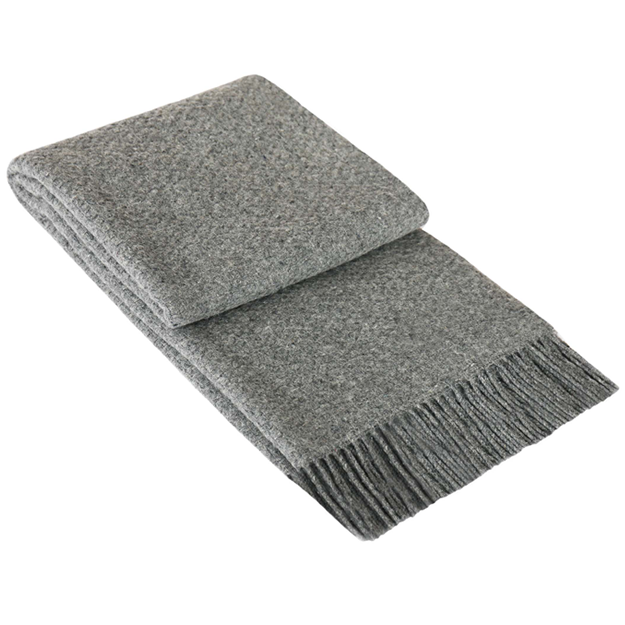 Soho Throw blanket in grey, made from a wool blend, elegantly draped on a cozy couch, showcasing its soft texture and stylish design.