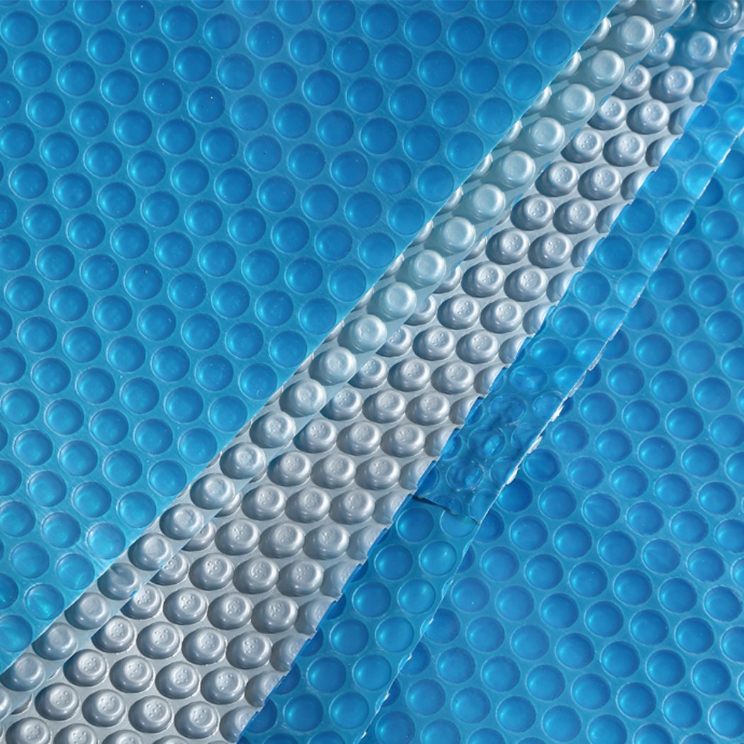 Solar Swimming Pool Cover with blue top and silver bottom, designed for warmth and cleanliness, featuring durable bubbles.