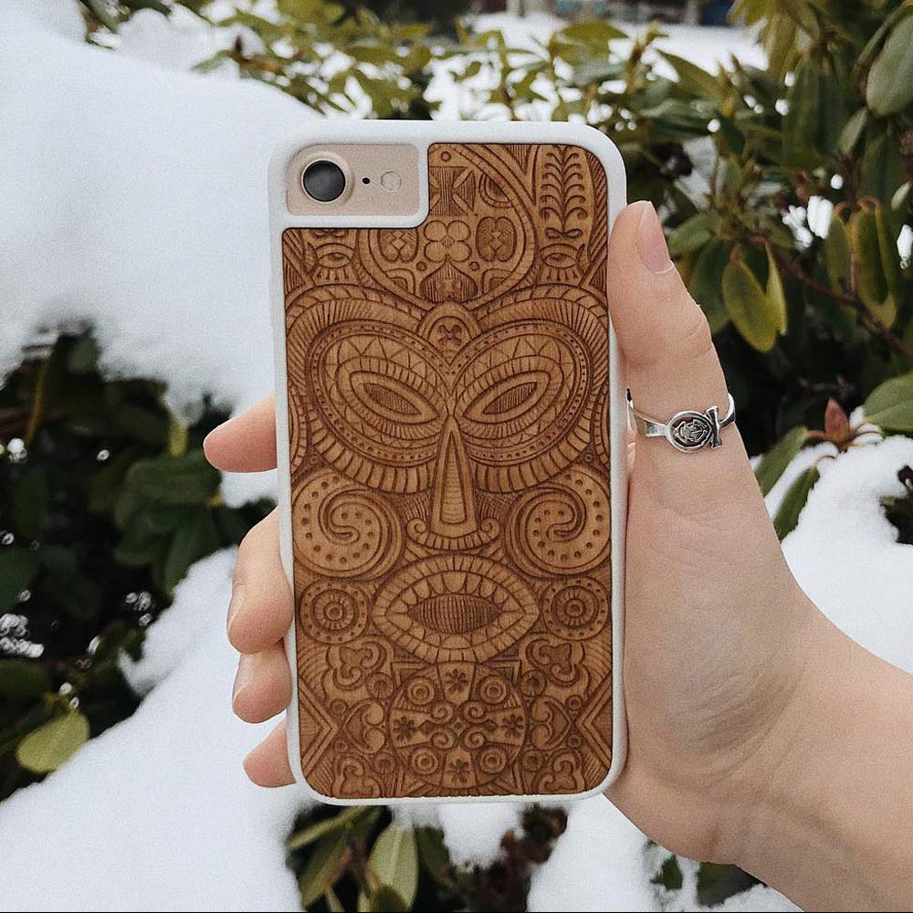 Tribal Mask wooden phone case held in hand, showcasing its unique design and natural wood grain.