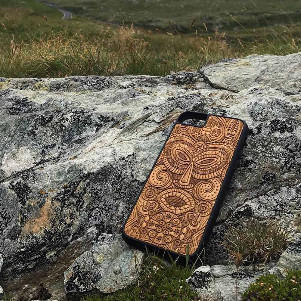 Tribal Mask wooden phone case held in hand, showcasing its unique design and natural wood grain.