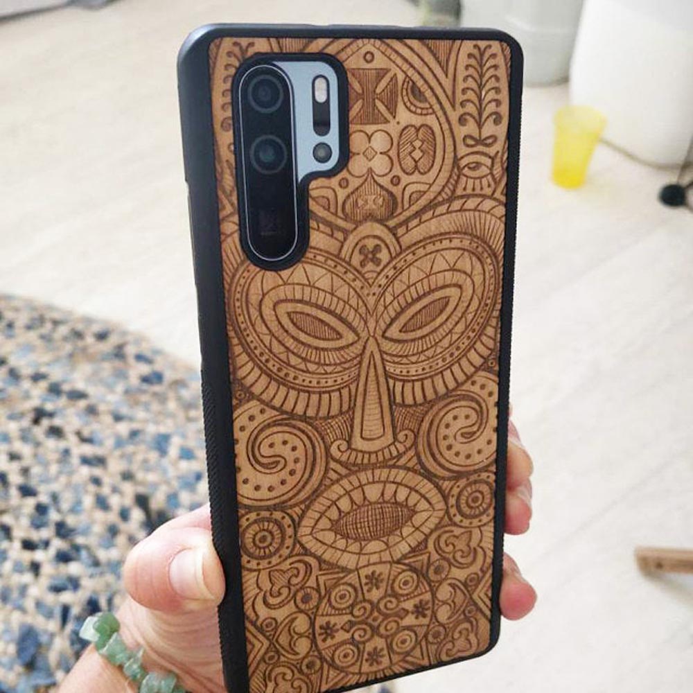 Tribal Mask wooden phone case held in hand, showcasing its unique design and natural wood grain.