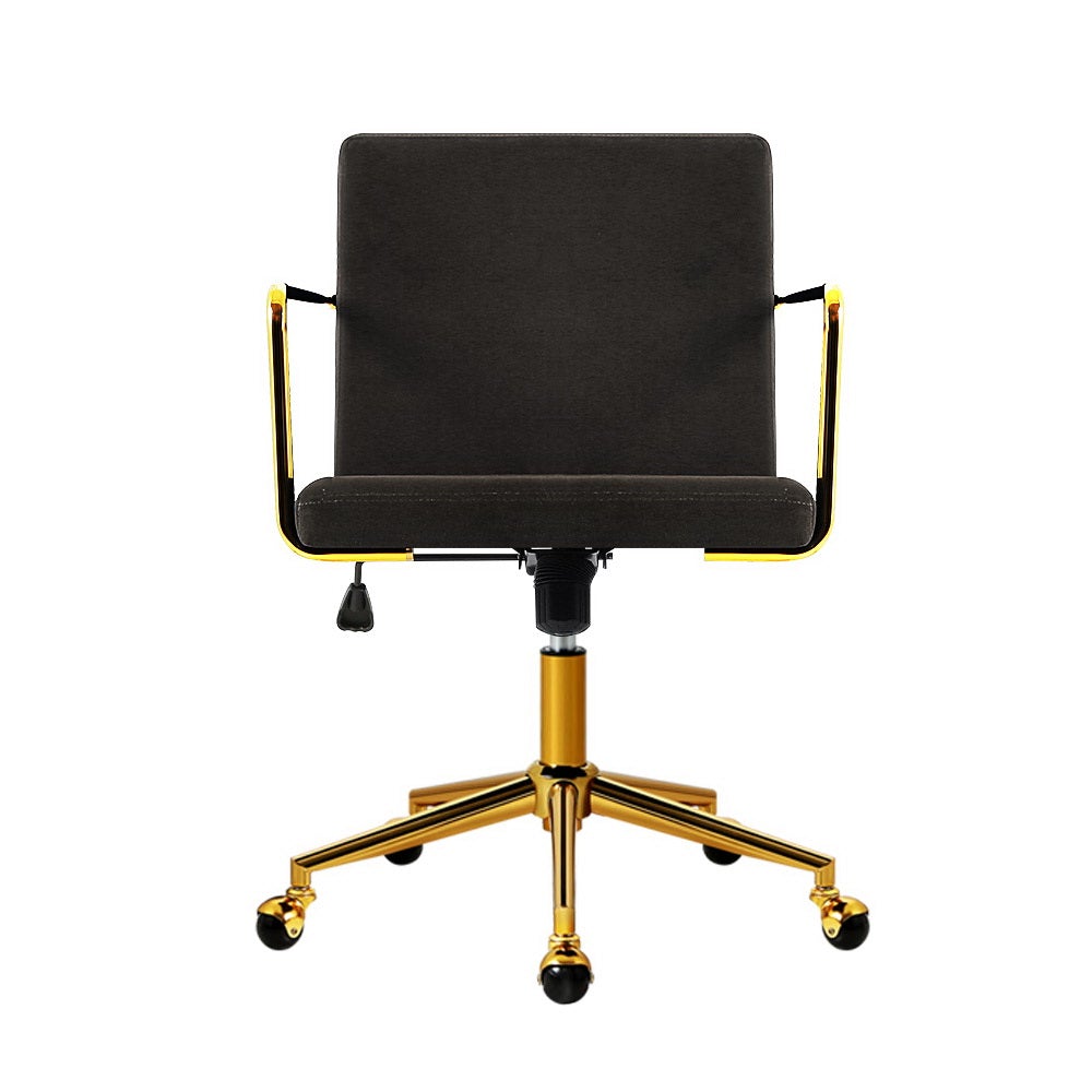 Caraway Velvet Office Chair with metallic brass base and armrests, showcasing luxurious charcoal upholstery and smooth castor wheels.