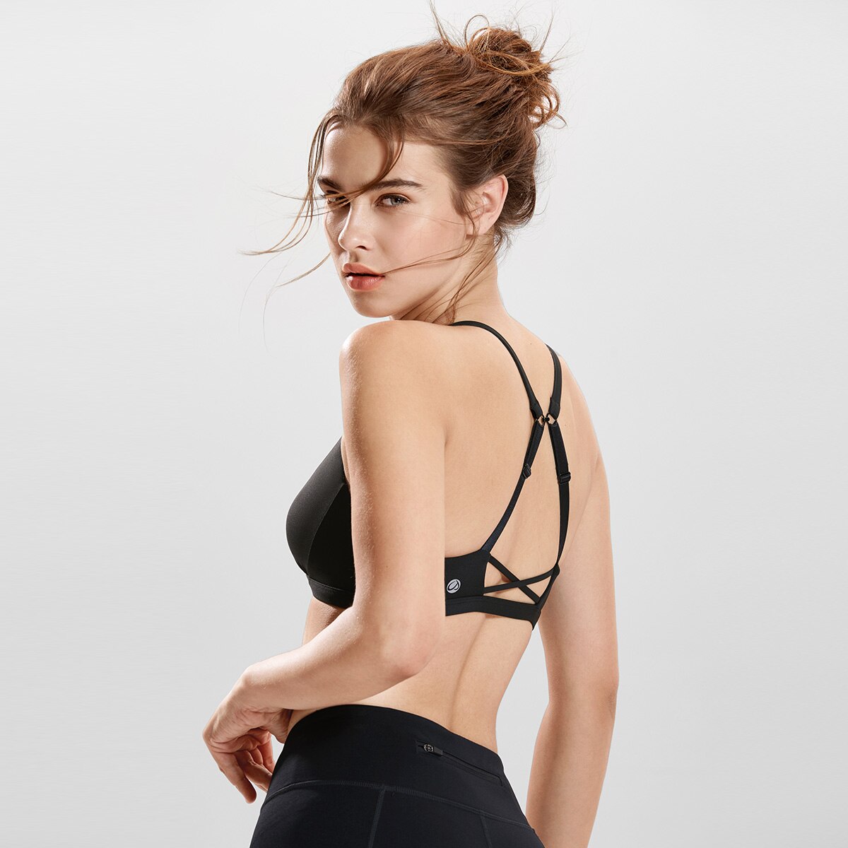 Women's Light Support Strappy Wirefree Yoga Bra in Black, showcasing removable pads and breathable fabric.