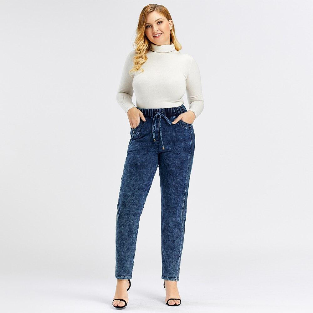 A pair of Women's Plus Size Casual Jeans featuring a mid-rise waist, full-length straight cut, and decorative sashes with lace-up details.