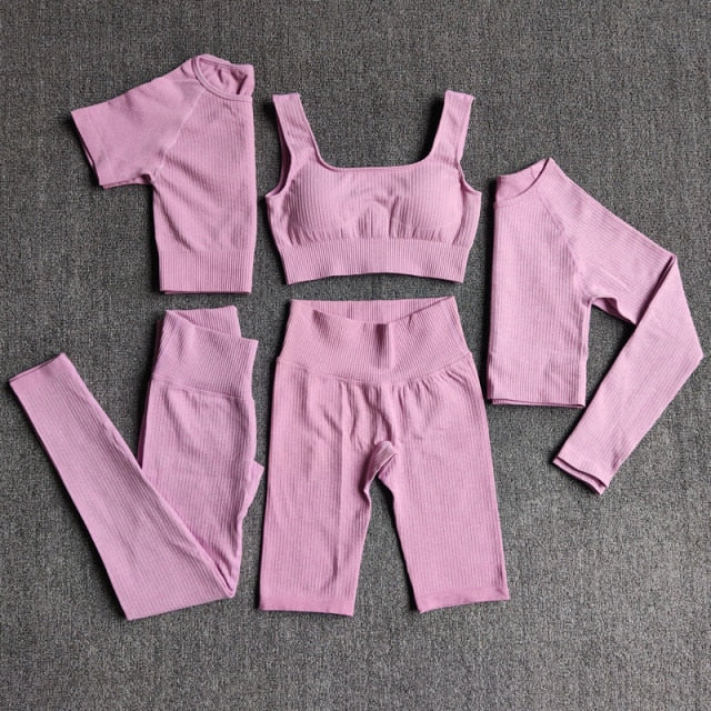 A stylish seamless yoga set for women, featuring leggings, a fitness bra, and a crop top in various colors including pink and black.