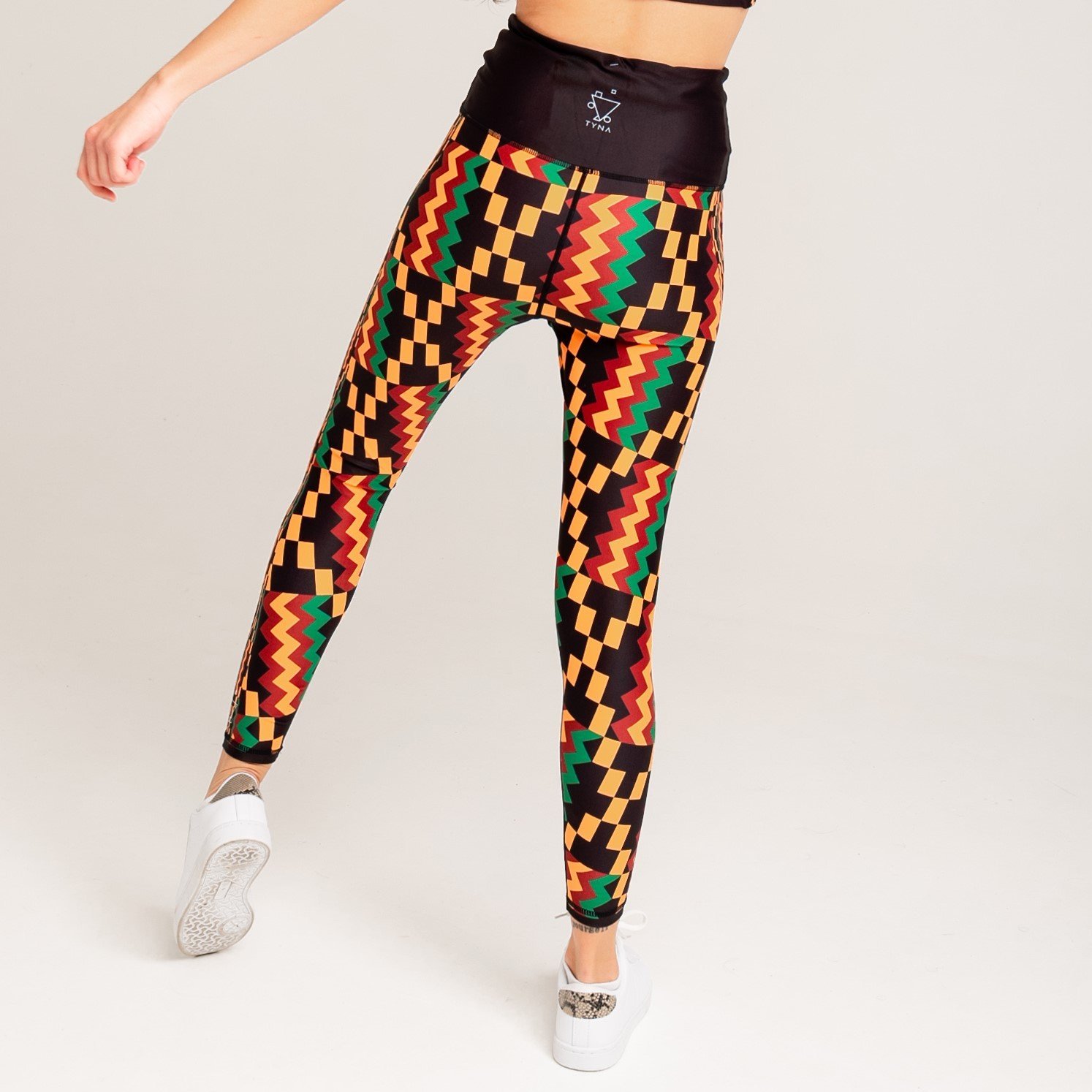 Kayentee Vibrant Leggings featuring bold geometric Kente cloth pattern in black, green, saffron, and flame colors, designed for comfort and performance.