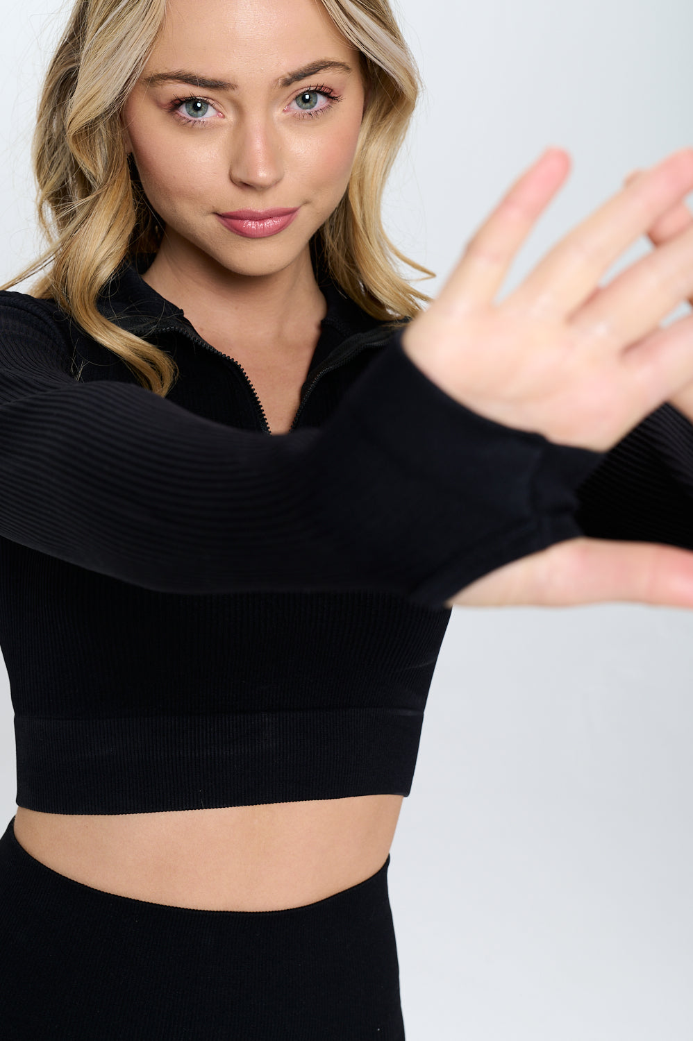 A stylish Seamless Half Zip Thumb Holes Crop Top in a stretchy knit material, featuring a high neckline and long sleeves, perfect for workouts.