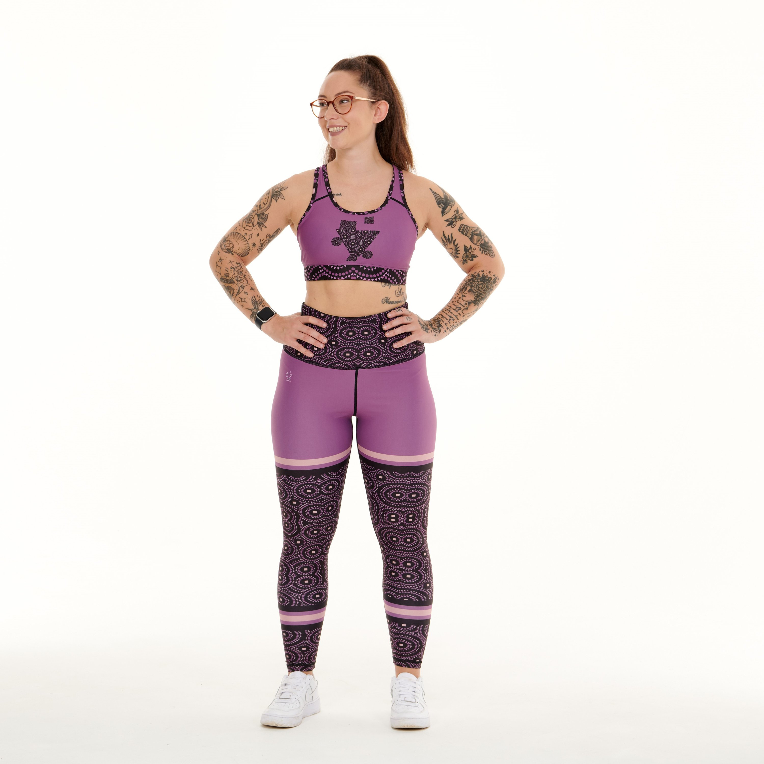 A pair of vibrant purple leggings featuring unique TYNA Signature Print with triangle, square, and circle shapes.