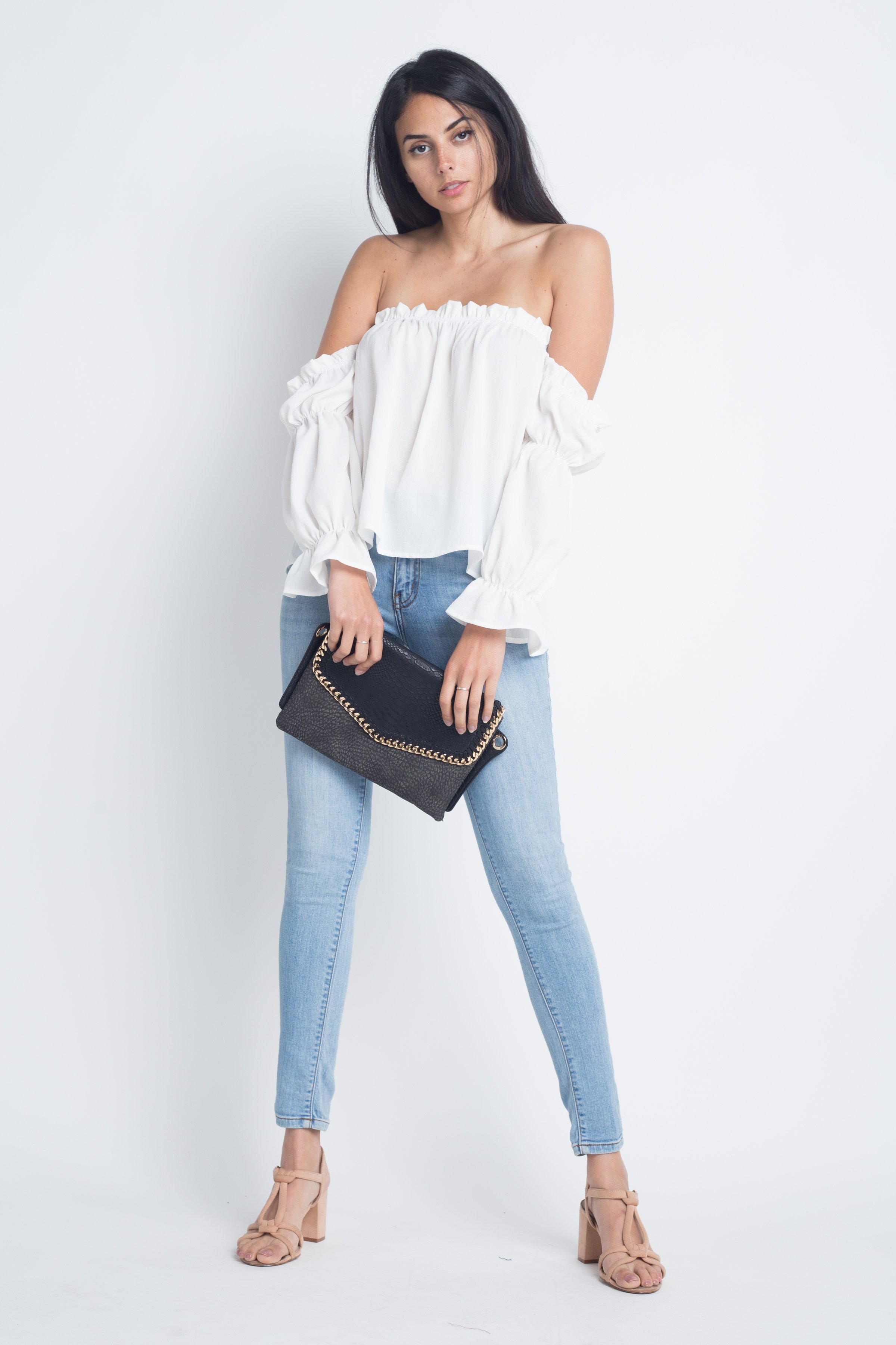 Woman in off-shoulder top holding clutch