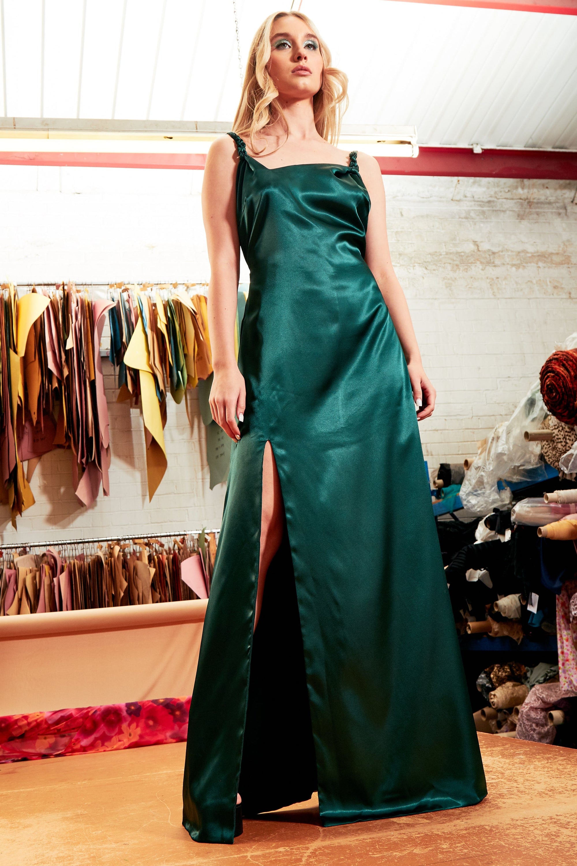 Elegant emerald green backless maxi dress with thigh-high slit and twisted spaghetti straps, perfect for formal occasions.