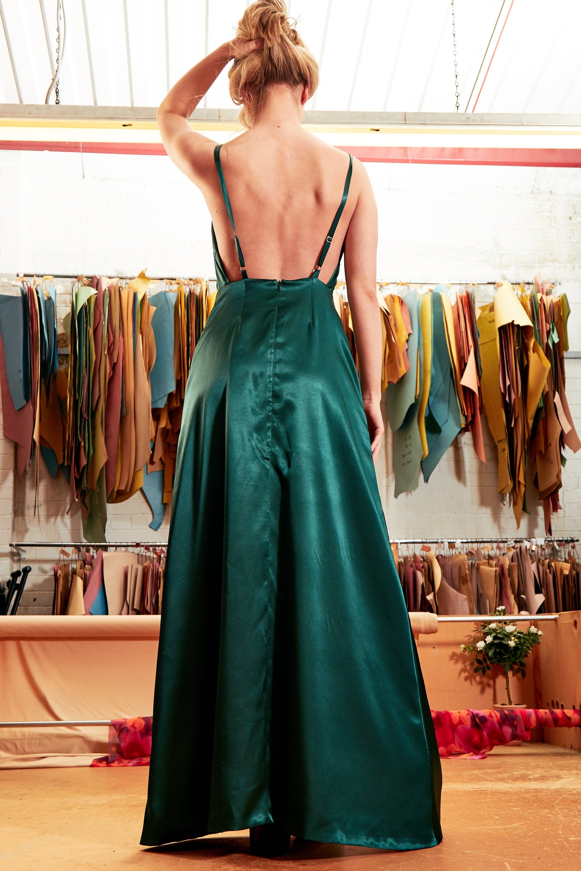 Elegant emerald green backless maxi dress with thigh-high slit and twisted spaghetti straps, perfect for formal occasions.