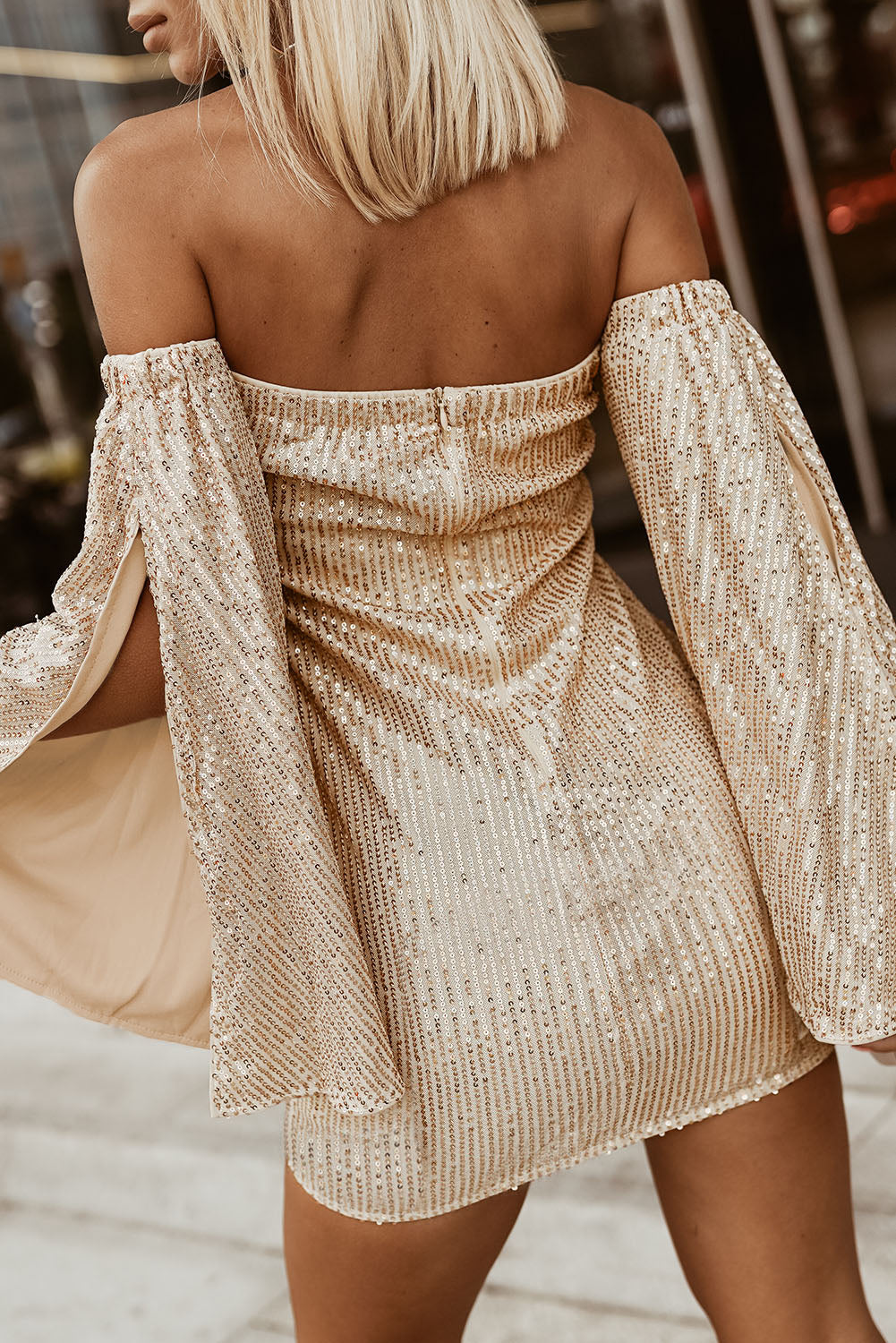 A glamorous bandeau club sequin dress with bell sleeves, showcasing sparkling sequins and a flattering above-the-knee length.