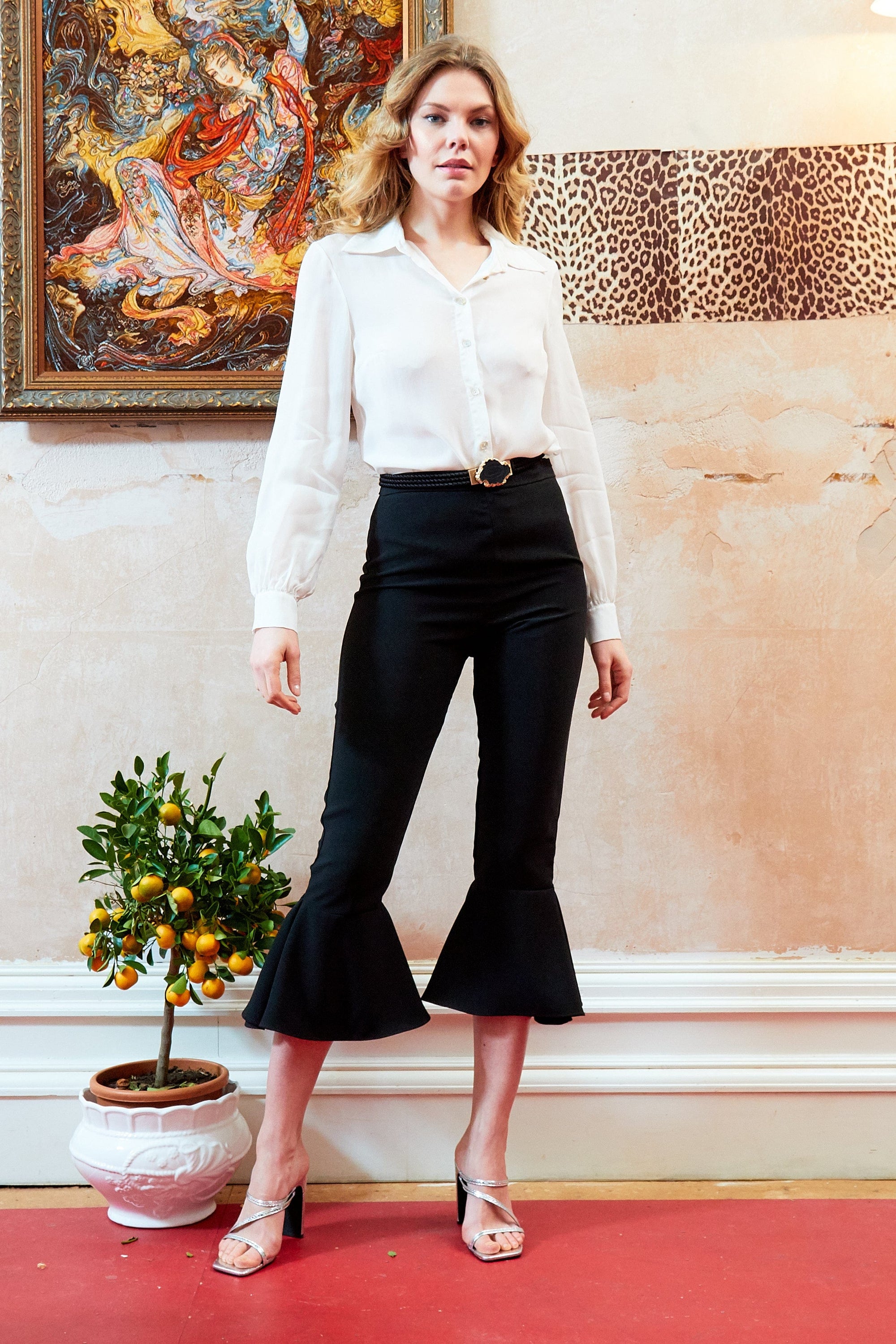 Elegant black frill hem trousers with a high waist and side zip closure, showcasing a stylish frill detail at the hem.