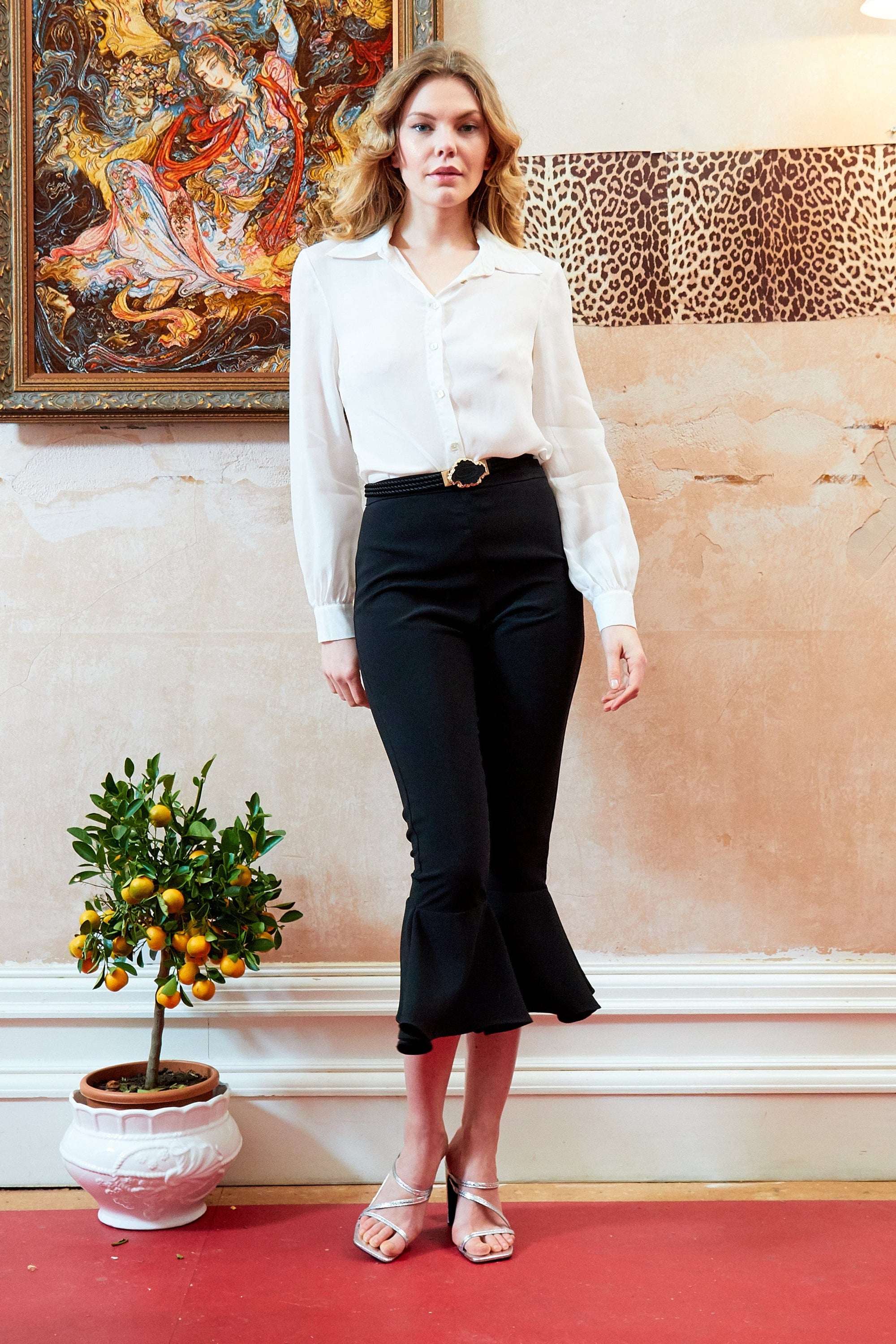 Elegant black frill hem trousers with a high waist and side zip closure, showcasing a stylish frill detail at the hem.