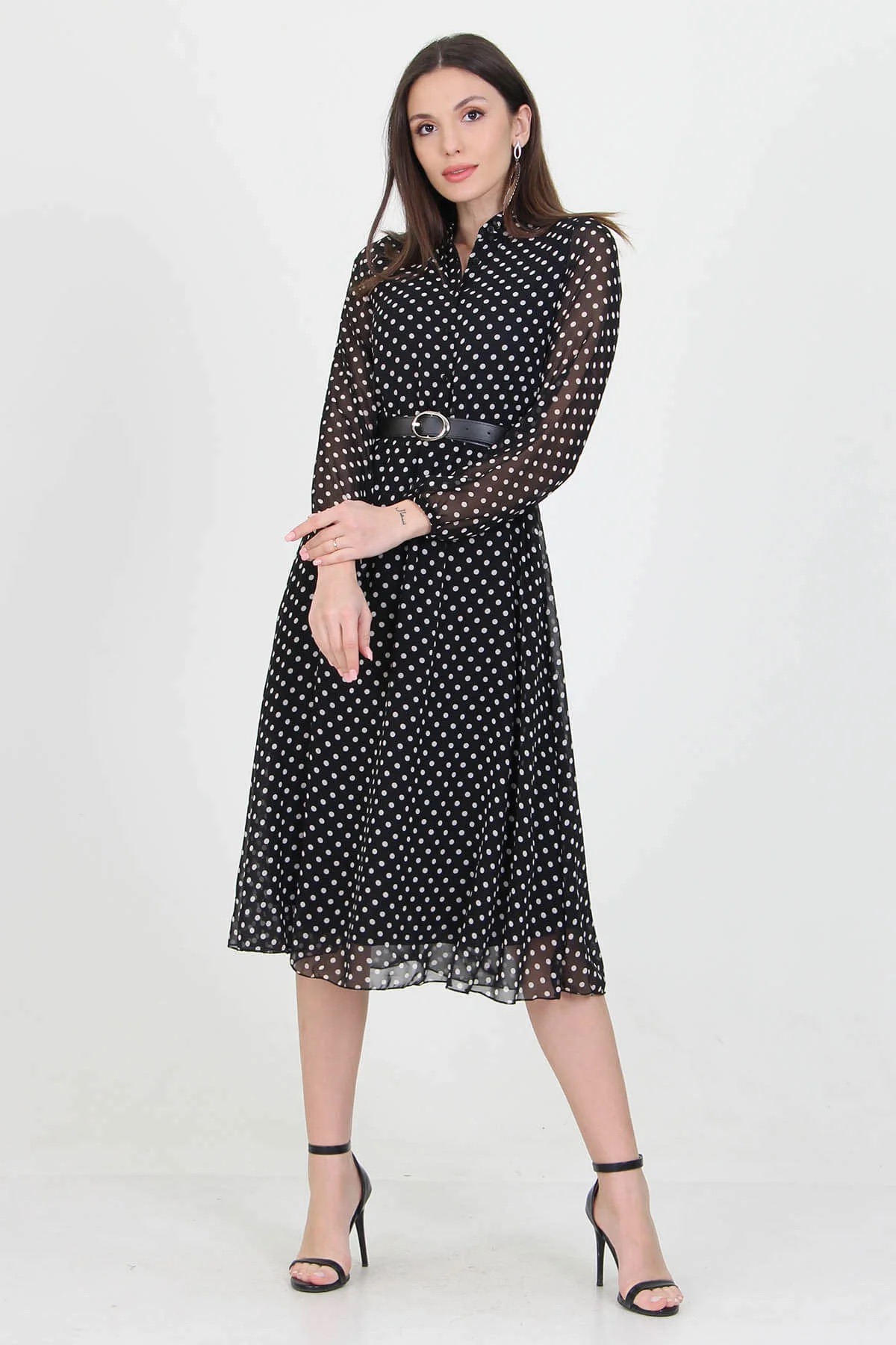 A stylish black polka dot dress hanging on a mannequin, showcasing its elegant design and playful pattern.