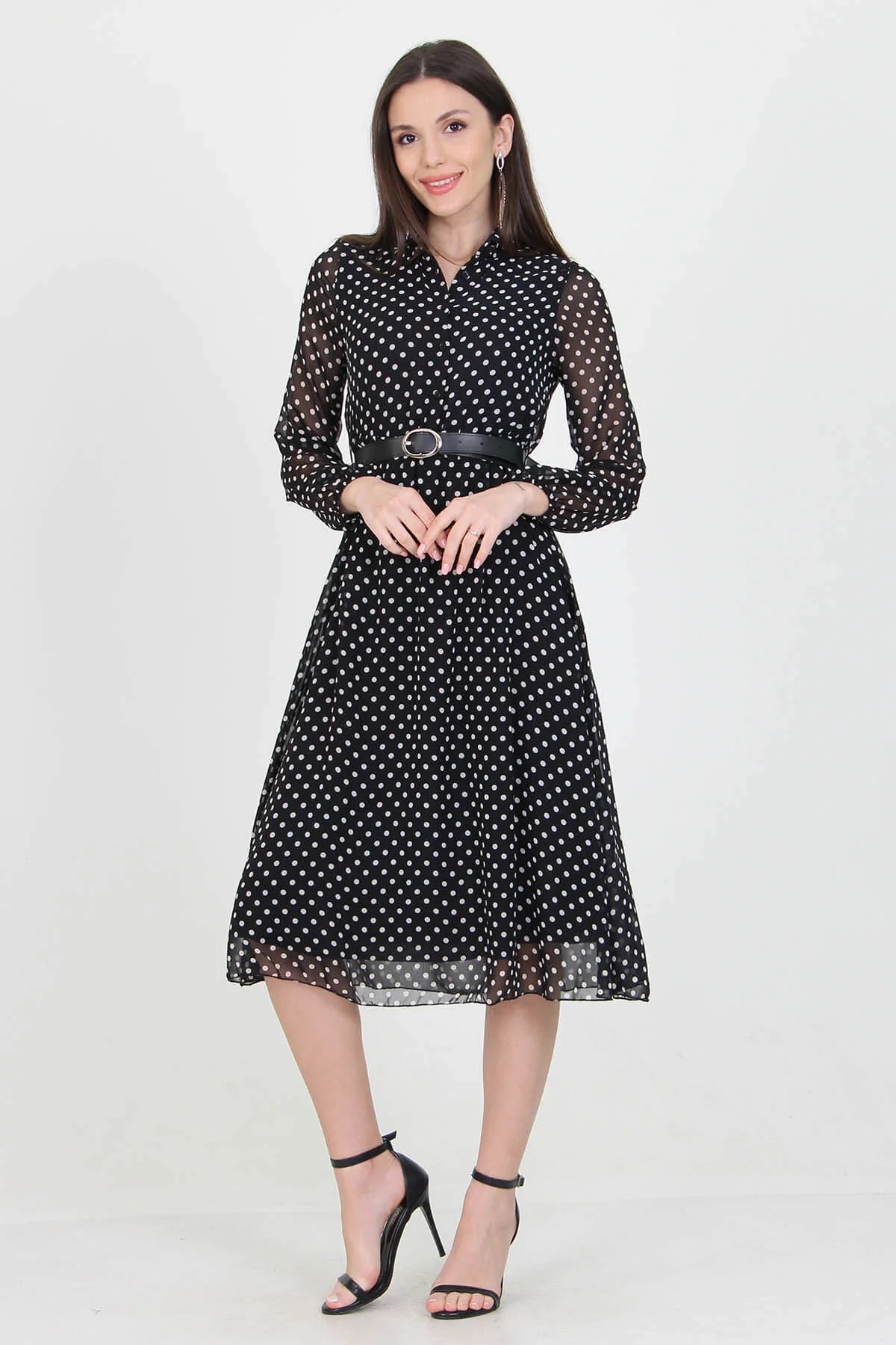 A stylish black polka dot dress hanging on a mannequin, showcasing its elegant design and playful pattern.