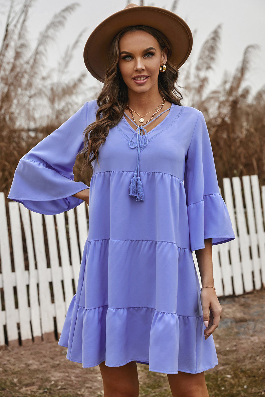 Cute sky blue cotton tiered babydoll tunic dress featuring a deep v-neckline, tassel tie, and ruffled bell sleeves.