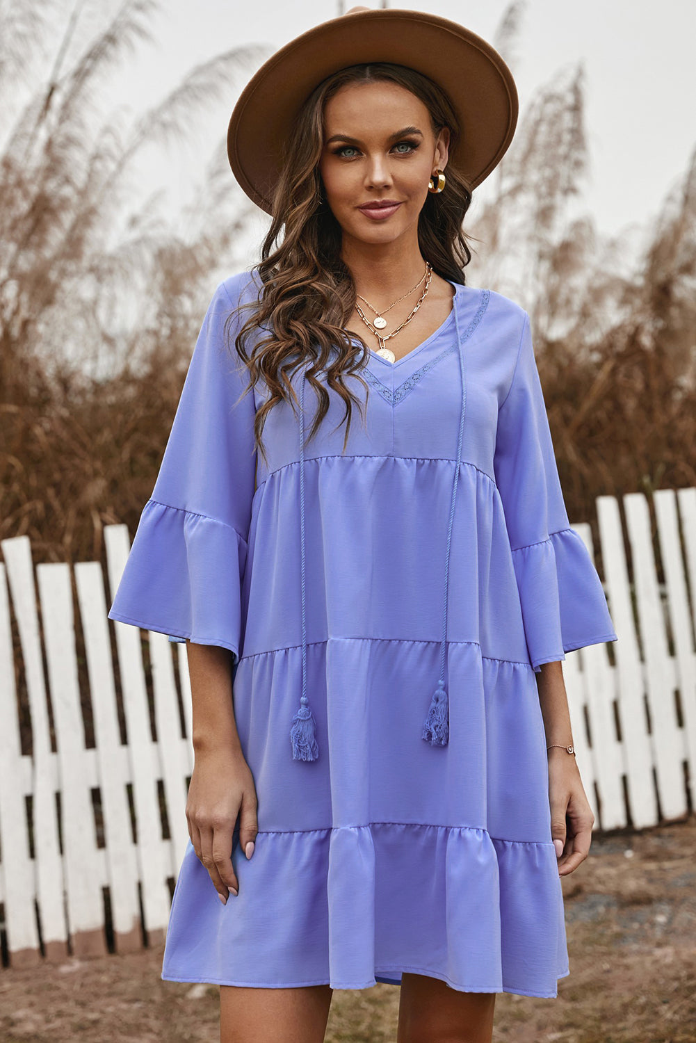 Cute sky blue cotton tiered babydoll tunic dress featuring a deep v-neckline, tassel tie, and ruffled bell sleeves.