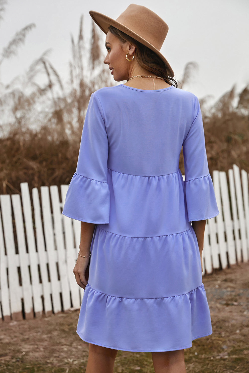 Cute sky blue cotton tiered babydoll tunic dress featuring a deep v-neckline, tassel tie, and ruffled bell sleeves.