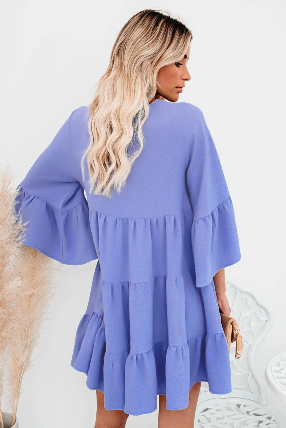 Cute sky blue cotton tiered babydoll tunic dress featuring a deep v-neckline, tassel tie, and ruffled bell sleeves.