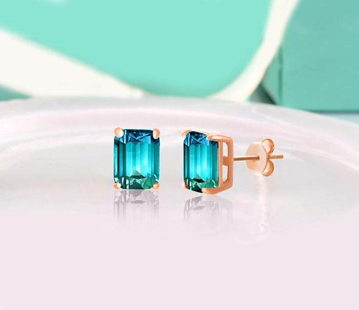 Elegant emerald cut white blue topaz stud earrings set in 18K gold, showcasing their stunning design and craftsmanship.