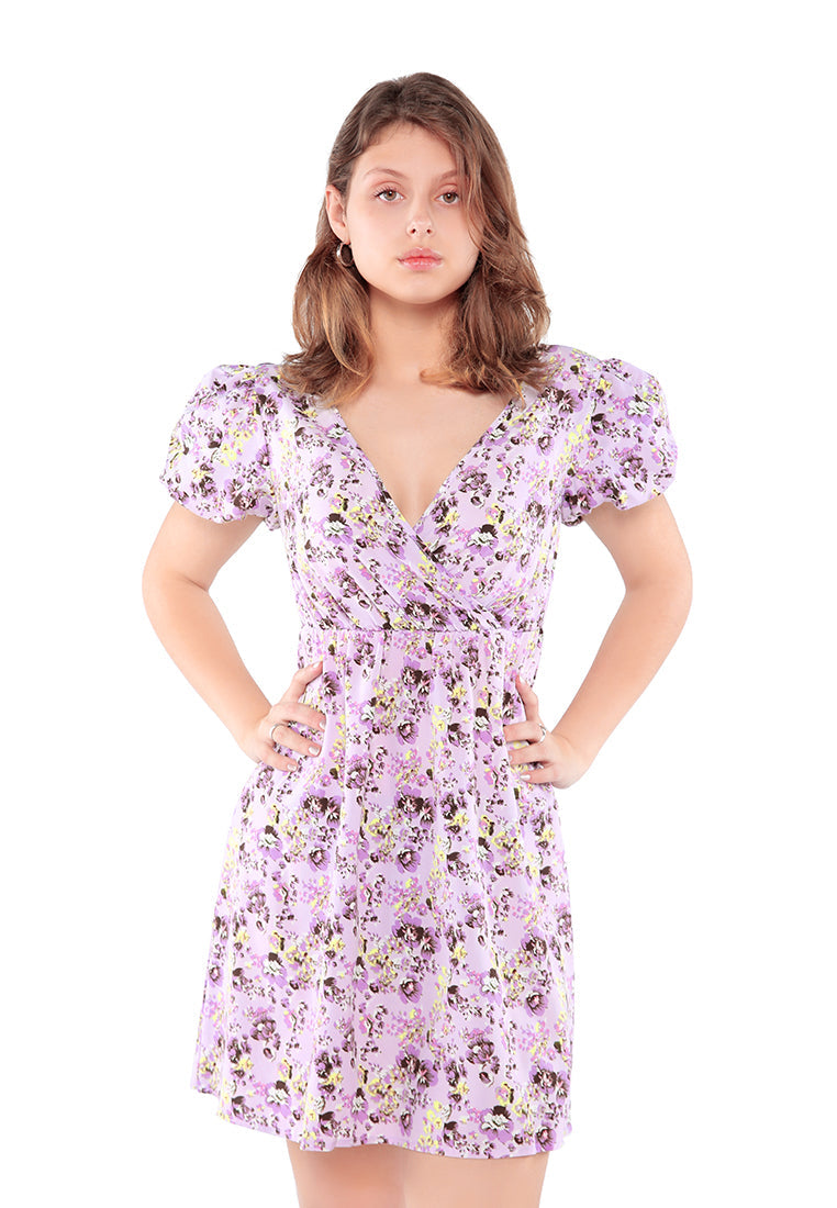 A stylish Floral Short Cut Out Dress featuring a wrap V neckline, short puffy sleeves, and a sexy cut-out back with tie-ups in light purple floral print.