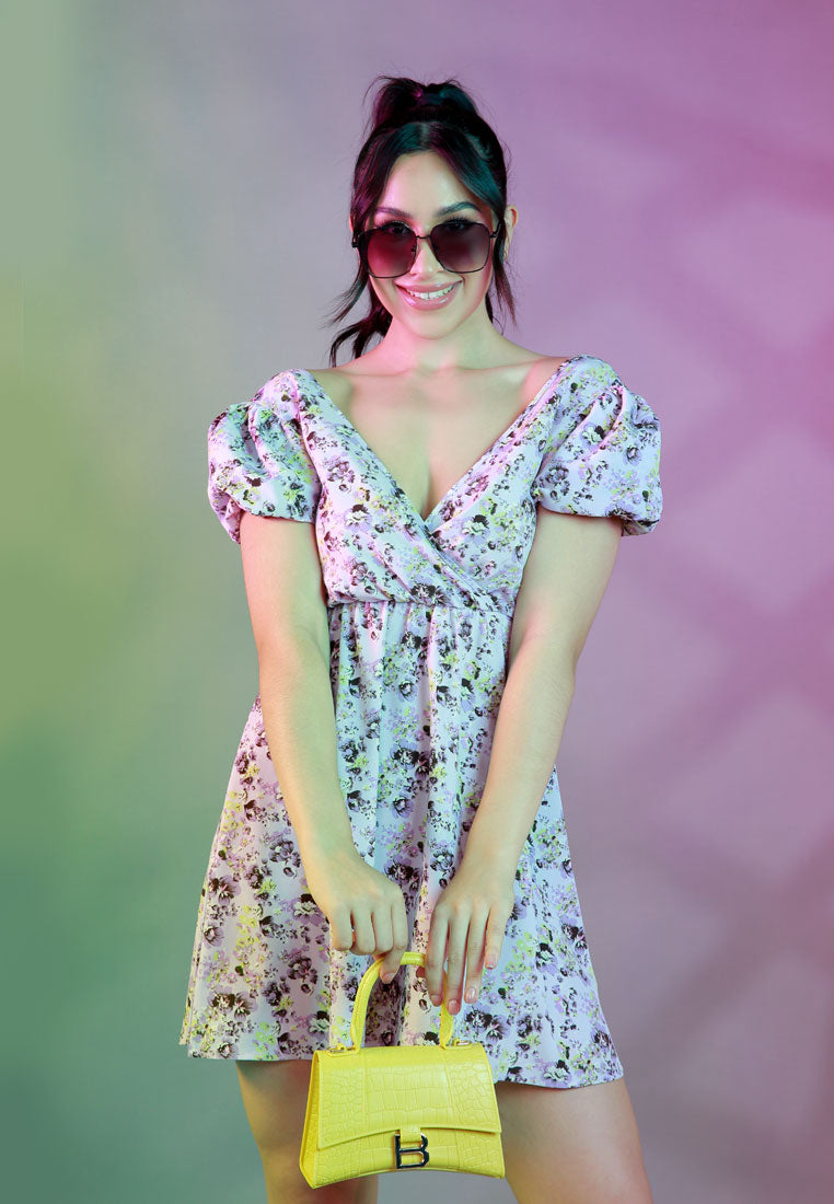 A stylish Floral Short Cut Out Dress featuring a wrap V neckline, short puffy sleeves, and a sexy cut-out back with tie-ups in light purple floral print.