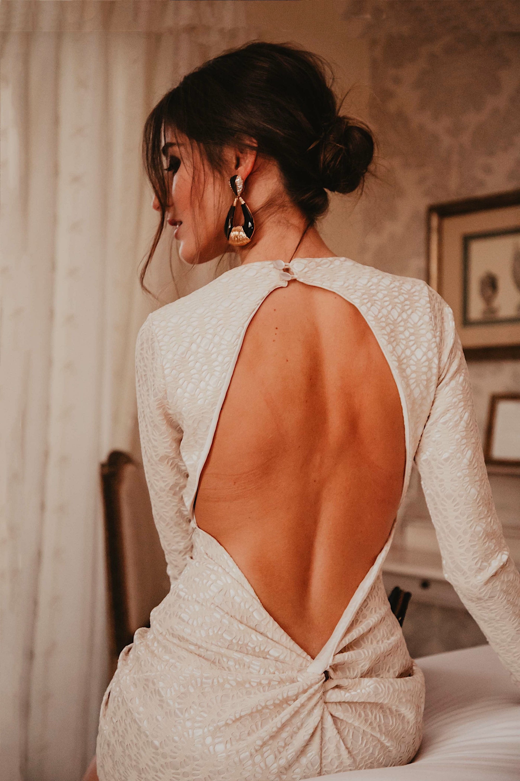 Ivory long sleeve backless dress with twisted knot detail, showcasing luxurious lace fabric and a bodycon fit.