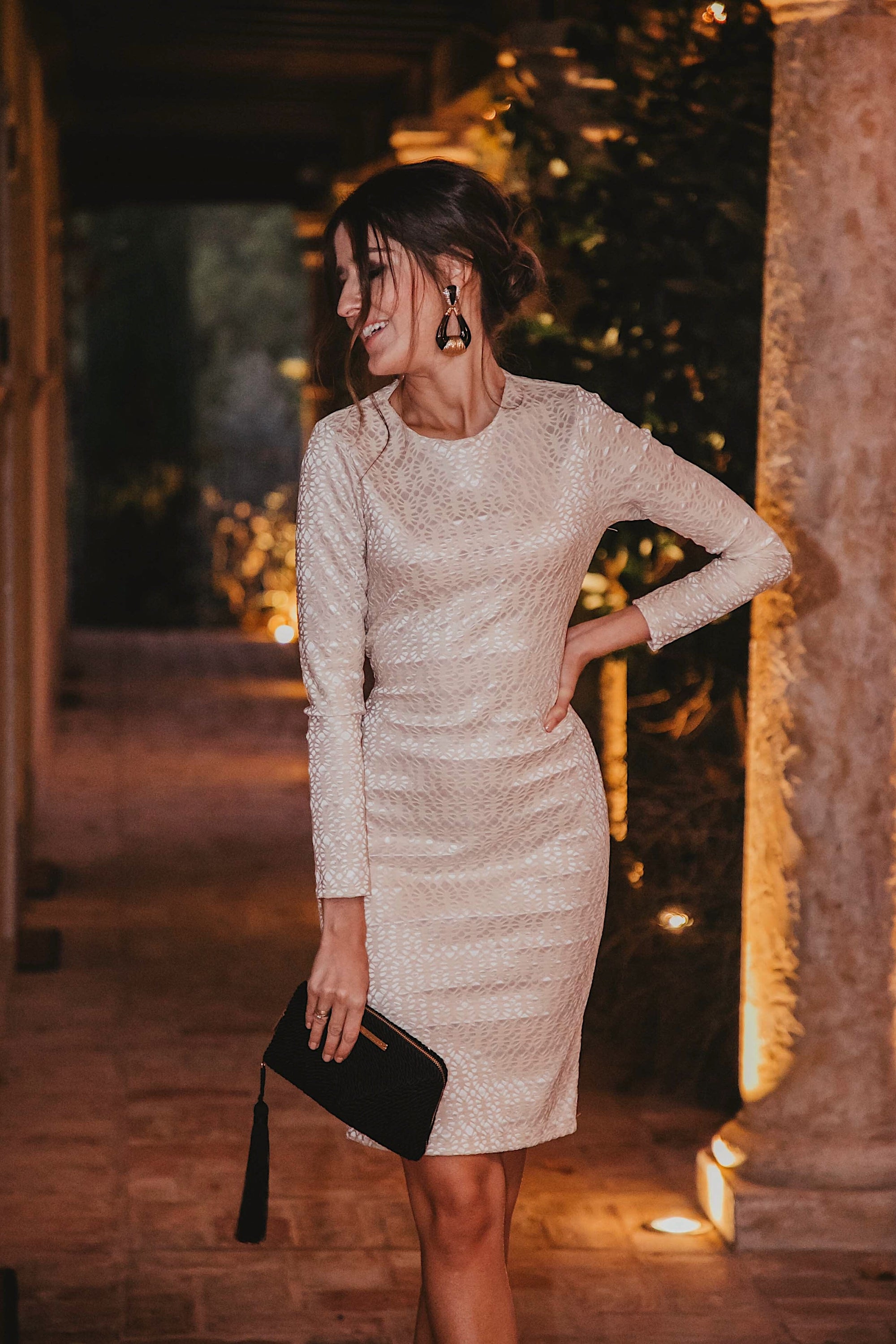 Ivory long sleeve backless dress with twisted knot detail, showcasing luxurious lace fabric and a bodycon fit.