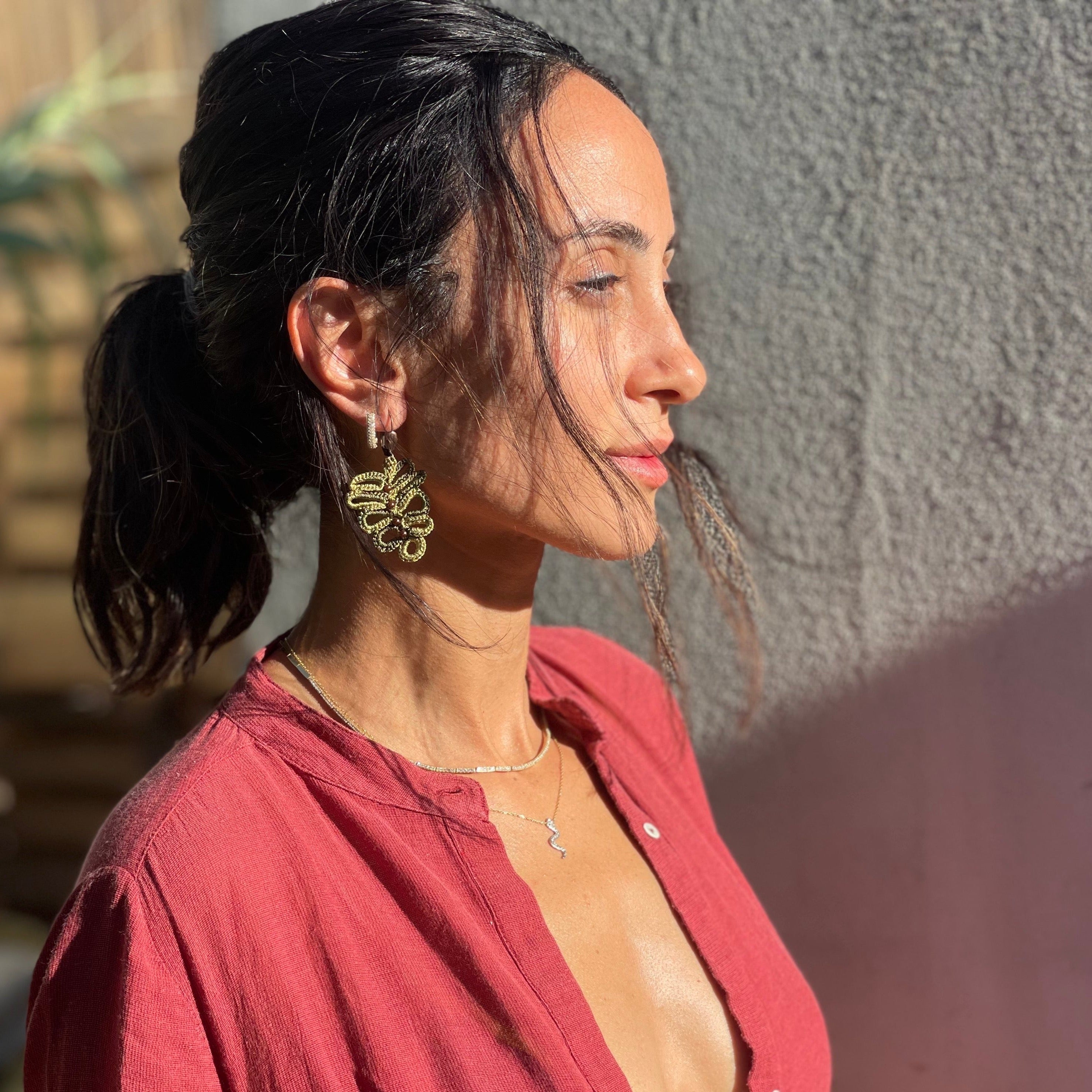 A pair of elegant leaf-shaped earrings adorned with gold-tone beads, showcasing their intricate design and craftsmanship.