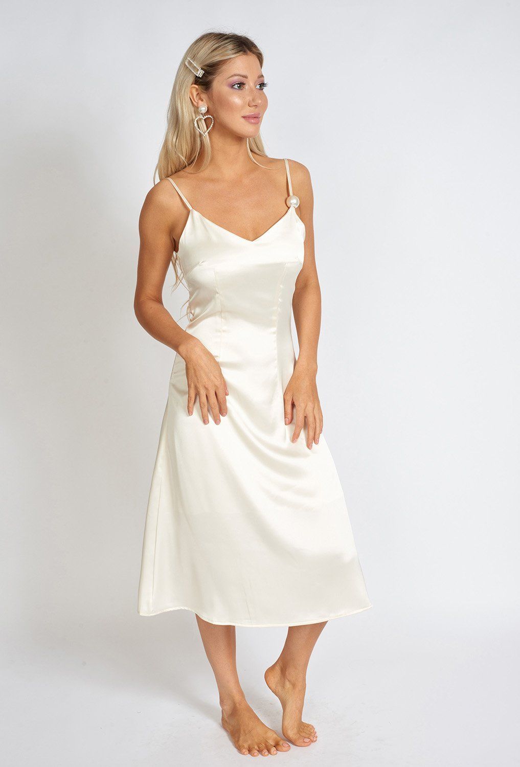 Léonie One Pearl Satin Slip Dress featuring a V-shaped neckline, thin adjustable straps, and a large pearl accent, showcasing its lustrous sheen.