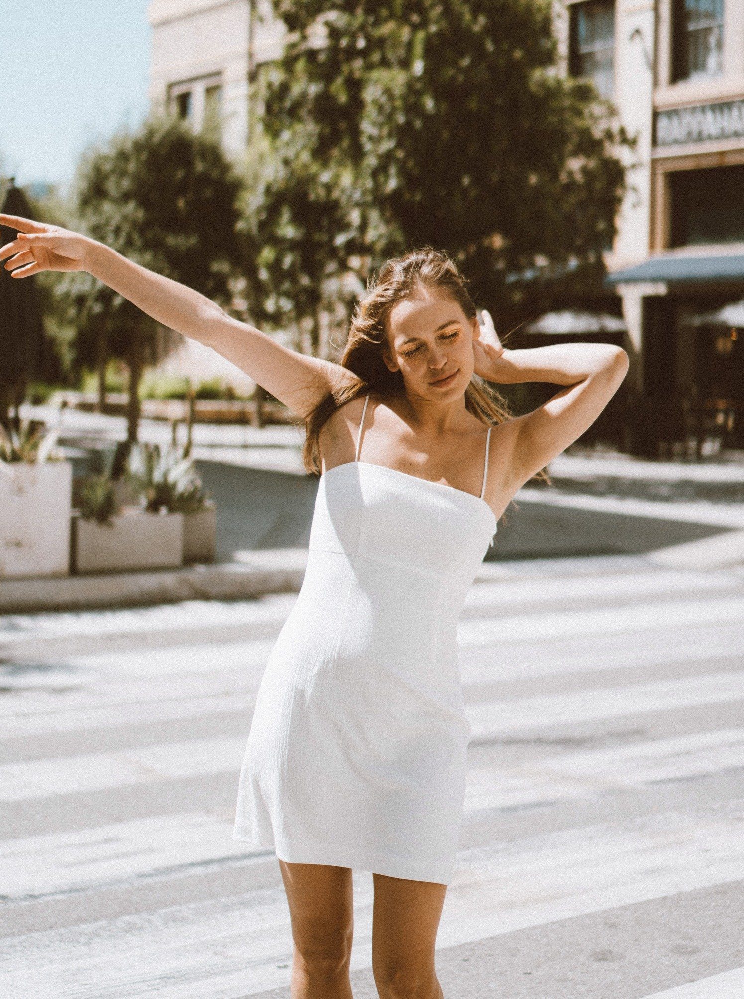 A stylish Melody White Mini Dress featuring a square neckline, spaghetti straps, and textured fabric, perfect for various occasions.