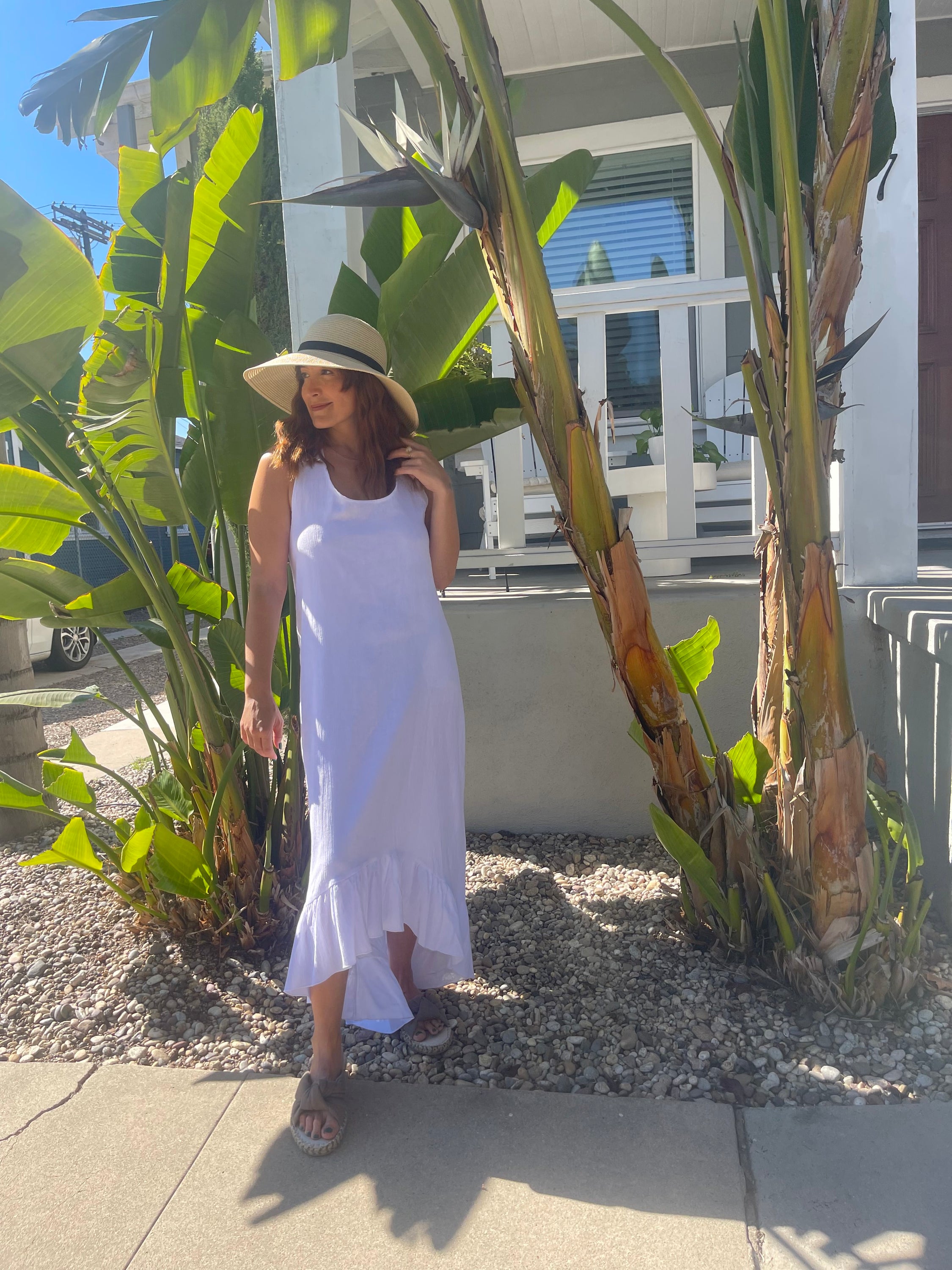 A stylish white maxi dress made from 100% Turkish cotton, featuring adjustable tie straps and a breezy silhouette, perfect for summer outings.