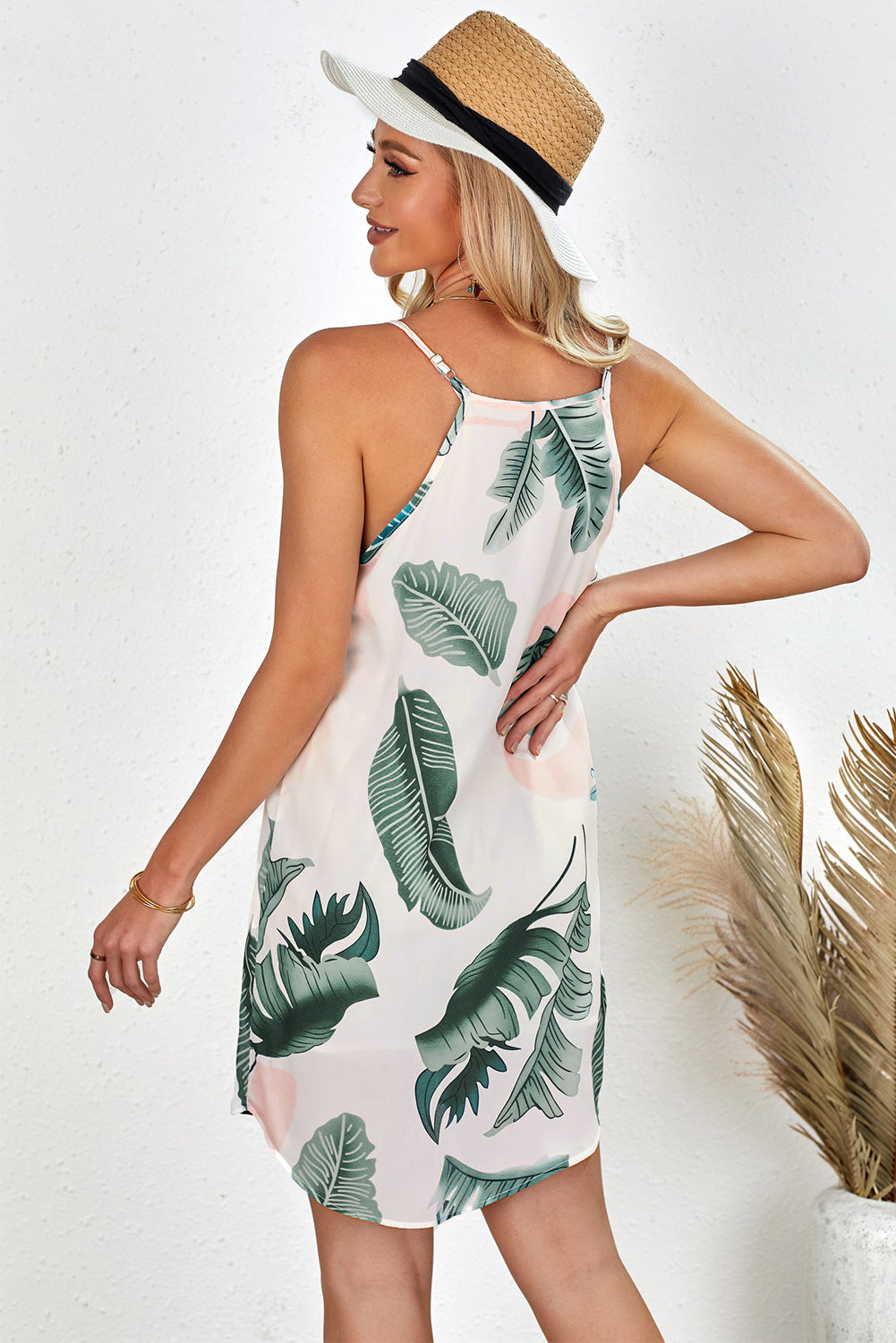 A stylish ivory sleeveless dress featuring a trendy palm tree leaf print, designed with a high neck and a mini length curved hem.