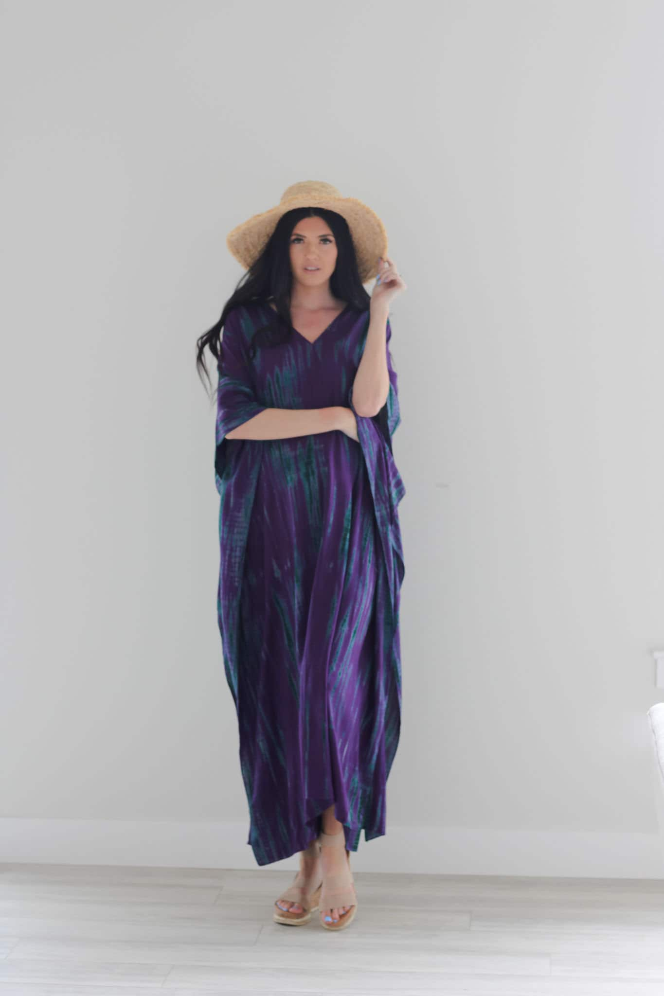 A vibrant purple tie-dyed kaftan dress with pockets, showcasing a v-shaped neck and flowing fabric, perfect for all body types.