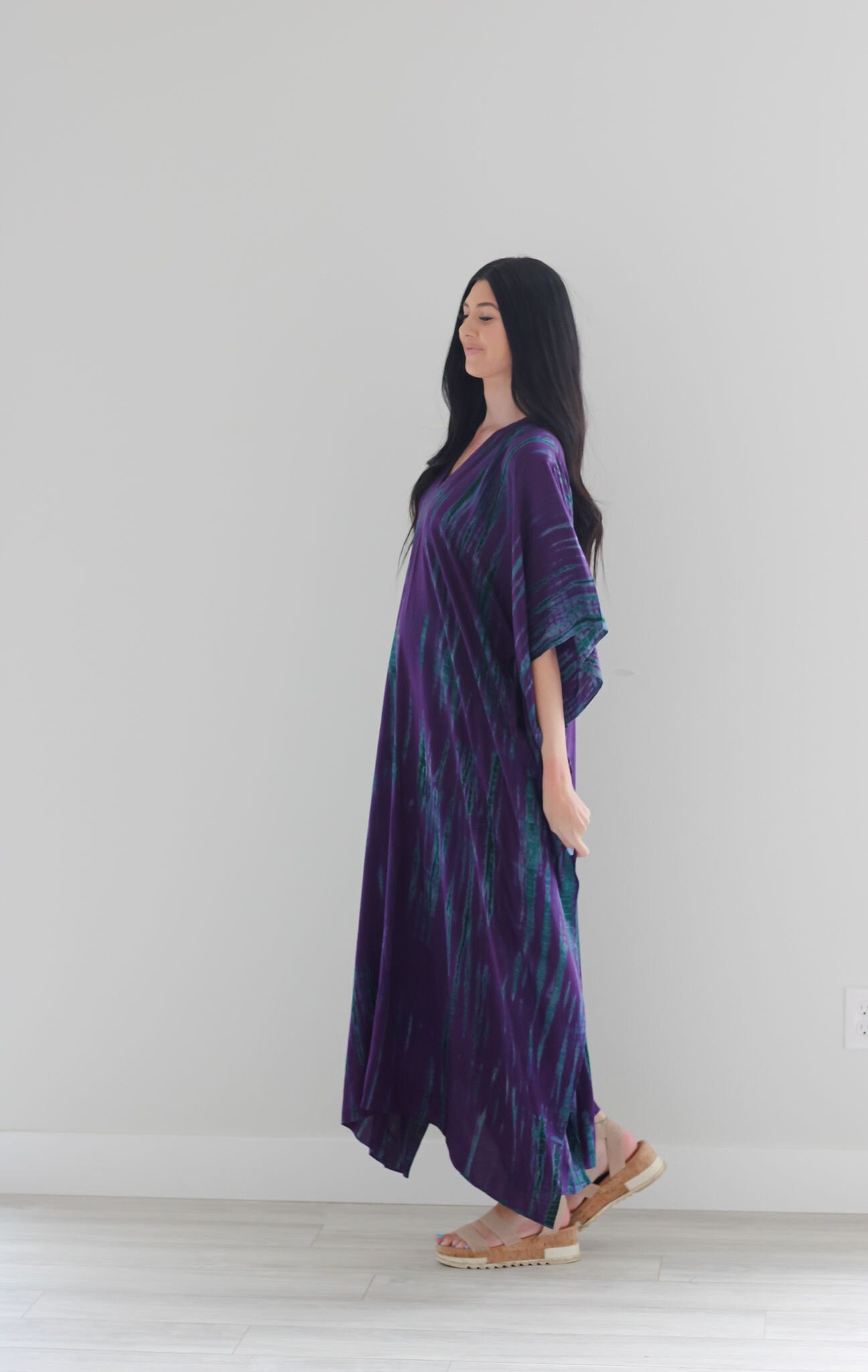 A vibrant purple tie-dyed kaftan dress with pockets, showcasing a v-shaped neck and flowing fabric, perfect for all body types.