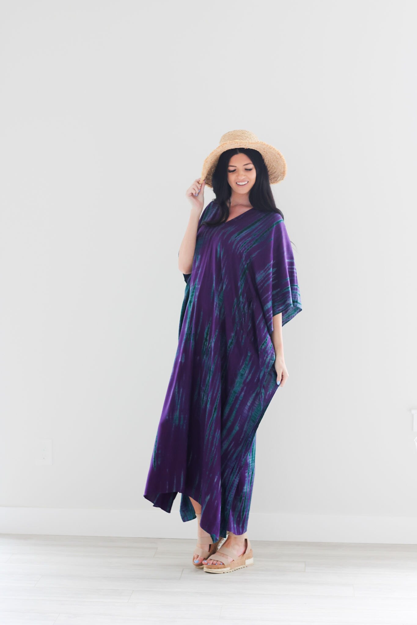 A vibrant purple tie-dyed kaftan dress with pockets, showcasing a v-shaped neck and flowing fabric, perfect for all body types.